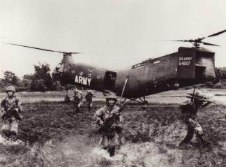 After leaving their CH-21 helicopter ARVN soldiers slog through the water of a rice paddy to begin an attack on the Viet Cong.