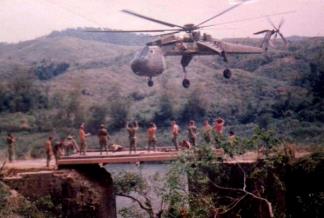 A CH-54 Sikorsky Skycrane delivers a bridge to route 9, 4-1/2 miles from Khe Sanh (I Corps).