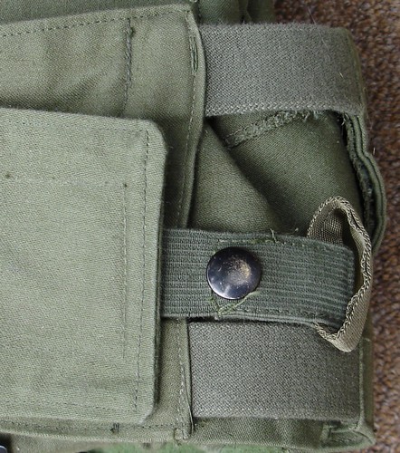The standardized aircrew armor vest had an elastic loop with a snap fastener attached to the outside overlapping waistband to prevent opening in the wind stream.