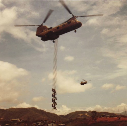 ARVN Rangers climb a long extraction ladder suspended from a hovering CH-46 Helicopter.