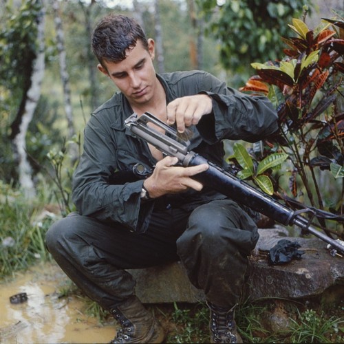 A rain soaked member of the 101st Airborne cleans his M16 rifle during Operation Wheeler.