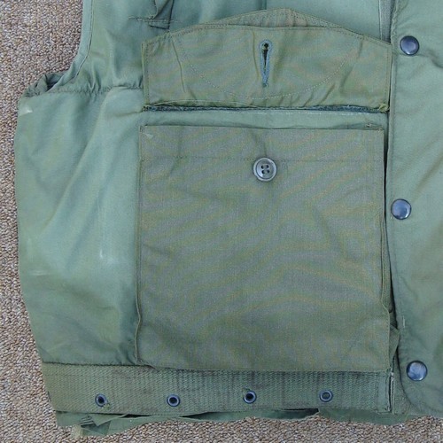The cargo pocket buttons on the 2nd pattern M1955 Flak Vest were concealed behind V-cut pocket flaps.