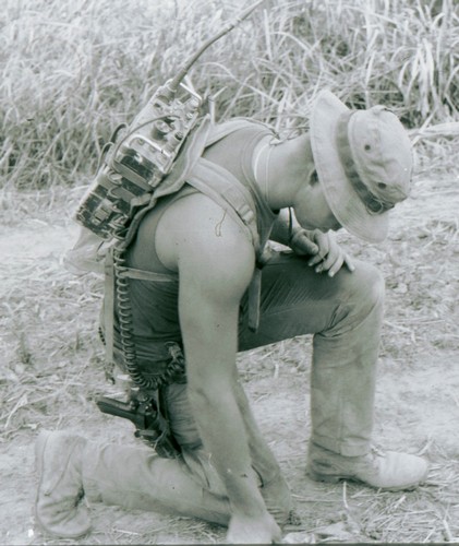 A Radio Telephone Operator (RTO) wears a boonie hat and uses an ST-138 harness to carry the PRC-25 on his back.