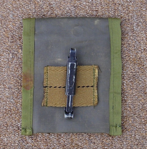 The single slide keeper on the back of a rubberized version of the M1967 First Aid / Compass pouch.